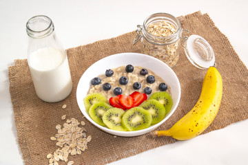 oatmeal for Breakfast with kiwi, strawberries and blueberries on sacking