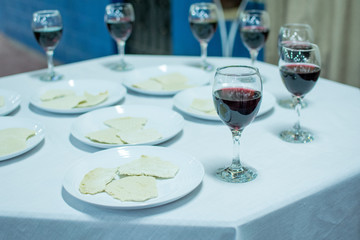 Ceremony table with white tablecloth with seven white plates with unleavened bread and in the background seven glasses of wine surrounding the table.
