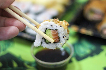 Hand chopstick sushi california uramaki avocado salmon soy sauce bowl take away, delivery, green towel tropical summer japanese food