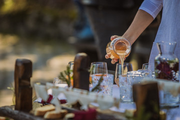 Glass water bottles or jars with water and juice, decorated with flowers on an event or fancy...