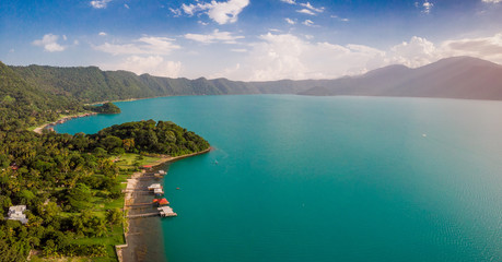 Aerial view of the coatepeque lake in El Salvador, where you can see the mountains that surround the lake, a sky almost clear only with some clouds, in the season where its waters turn turquoise.