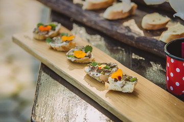 Small appetizer sandwiches on a wooden board, ready to be eaten. Fresh bread with truffles cream and decoration on a wooden serving board.