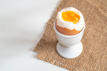 a boiled egg standing on a sacking on a stand close up