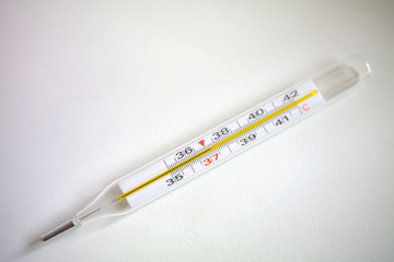 mercury thermometer for measuring temperature in medicine on a white background with a temperature of 37.2