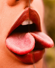 Boca de una mujer sacando la lengua siendo reflejada en un espejo provocando un ilusión doble. 