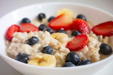 delicious Breakfast, oatmeal porridge with fruit slices strawberry, banana and blueberries