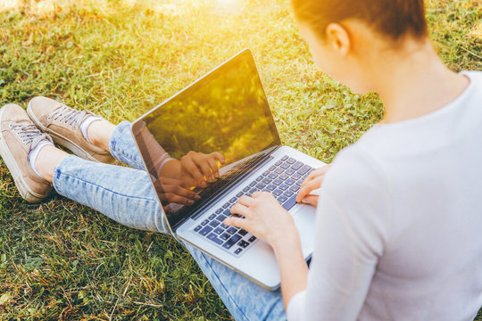 Mobile Office. Freelance Business Concept. Young Woman Sitting On Green Grass Lawn In City Park Working On Laptop Pc Computer. Lifestyle Authentic Candid Student Girl Studying Outdoors.