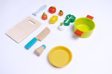 Vegetables, pot, fish and kitchen utensils toys made from wooden for kids to play on top of white background