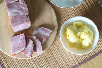 Russian homemade meal with mashed potatoes and smoked pork bacon on a bamboo mat and a wooden table.