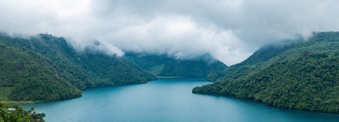 Aerial view of the Laguna Brava in Guatemala, on a cloudy day where you can see its turquoise water and the beautiful mountains that surround the lake. © Daniel Umana 😎📸
