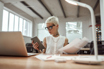 Making business easier. Young and beautiful tattooed business woman wearing glasses working with...