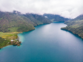 Aerial view of the Laguna Brava in Guatemala, on a cloudy day where you can see its turquoise water and the beautiful mountains that surround the lake.