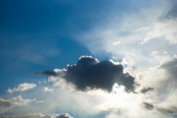 Dark cloud obscuring sun on deep blue sky
