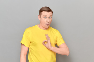 Portrait of surprised amazed blond mature man showing okay gesture