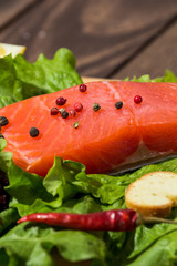 red fish fillet on a wooden background. trout, lettuce, crackers, toasts, red pepper. preparing breakfast