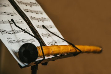 closeup scene of an oriental musical instrument Ney, stays on the music sheet stand with notes,...