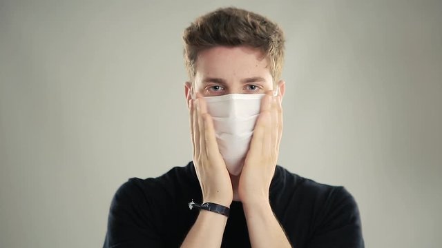 Young boy with blue eyes shows how to put on a surgical mask to protect himself from infections by the respiratory tract. Covid-19 coronavirus. Bust. Isolated