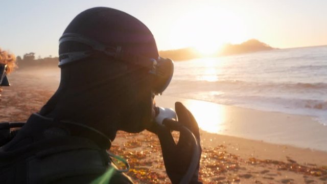 Scuba divers talking while standing on shore at Monastery Beach during sunset - Carmel by the Sea, California