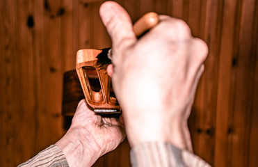 closeup scene of polishing wooden musical instrument with brush, in workshop, highlighted perspective with opposite angle