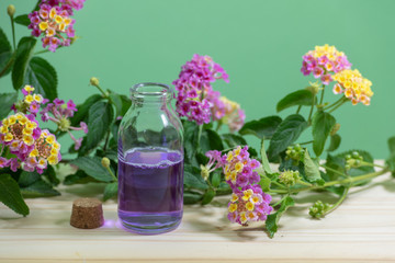 Botella de vidrio de aceite esencial azul con un tapón de corcho, rodeado de flores.