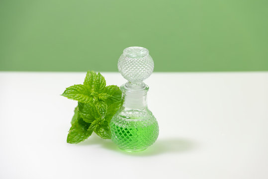 Aceite esencial de menta natural en una botella de vidrio con hojas de menta fresca
