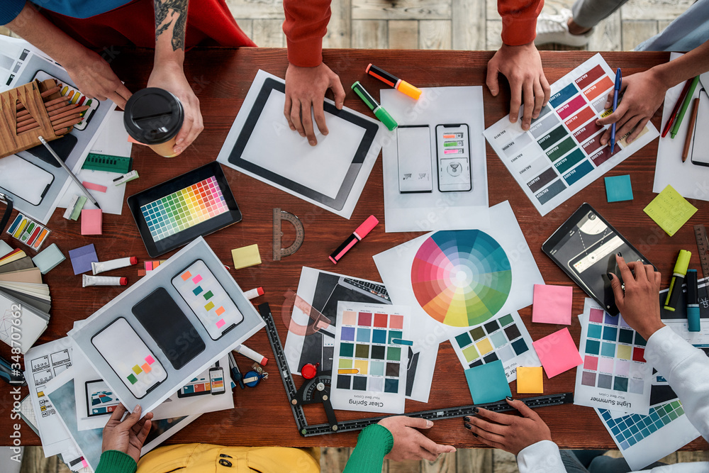 Poster working on a new project together. top view of designers discussing sketches, choosing colors from p