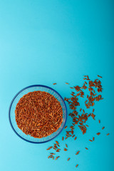 Glass jar with brown rice on a blue background.