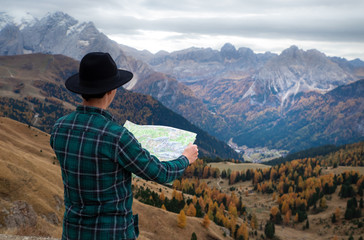 Fototapeta na wymiar young man with a map in the mountains. Hiking concept, lifestyle, traveler. Italian Alps, Dolomites