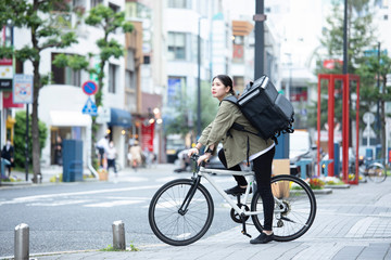 自転車で荷物の配送を行う若い女性