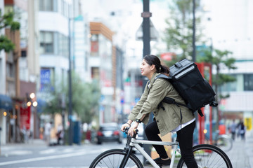Fototapeta premium 自転車で荷物の配送を行う若い女性