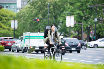 Obraz premium 自転車で荷物の配送を行う若い女性