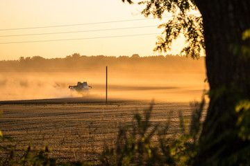 Fog over field with combine harvester in meadow