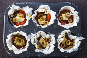 plant-based food, filo pastry cups with vegan filling made of tomatoes olives pesto and dairy-free cheese