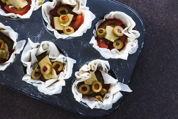 plant-based food, filo pastry cups with vegan filling made of tomatoes olives pesto and dairy-free cheese