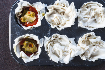 plant-based food, filo pastry cups with vegan filling made of tomatoes olives pesto and dairy-free cheese