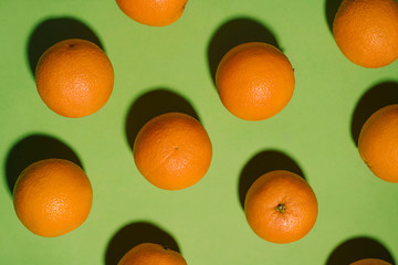 Fruit pattern with fresh oranges on green paper background. Top view. Summer concept
