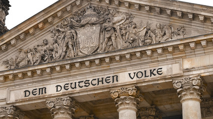 Reichstag. Facade Deutscher Bundestag. The upper part, the roof of the German parliament with many beautiful sculptures.The dedication Dem deutschen Volke,meaning To the German people, on the frieze.