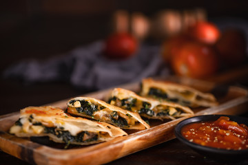 mexican food background of sliced chicken quesadilla with sauce in dark tone