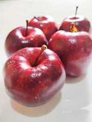 Apples on a white plate. Apples are rich in vitamin C, vitamin B6 and vitamin B1. One apple contains moderate (approximately 180 grams) contains 8.4 mg of vitamin C. Top View Shot. Selective Focus.
