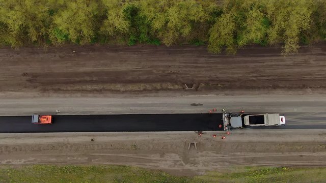 Roller machines make new asphalt roads. The asphalt paver squeezes hot asphalt.