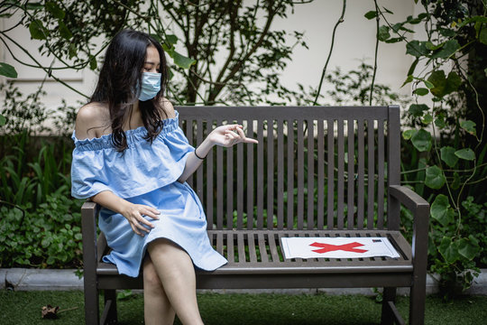 Woman  Social Distancing Sitting On Bench In Park