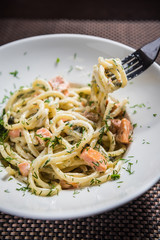 Spaghetti carbonara on a white dish with dill
