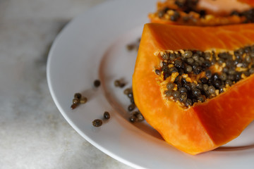 Fresh cut papaya on a white plate with black seeds