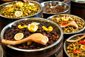 Range of different kinds olives arranged in wooden barrels.