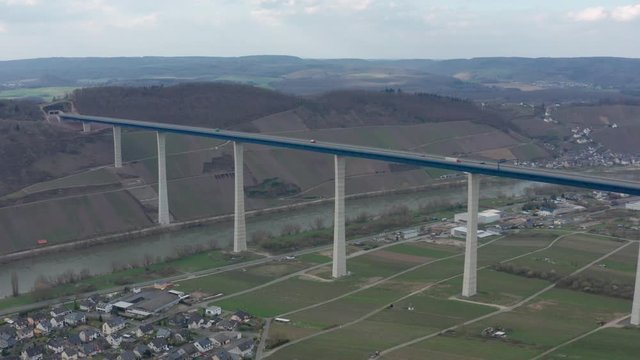 Hochmoselbr&uuml;cke High Moselle Bridge in Rhineland-Palatinate Germany with cars and trucks on a freeway highway cinematic panorama aerial drone shot on a sunny cloudy day 25p