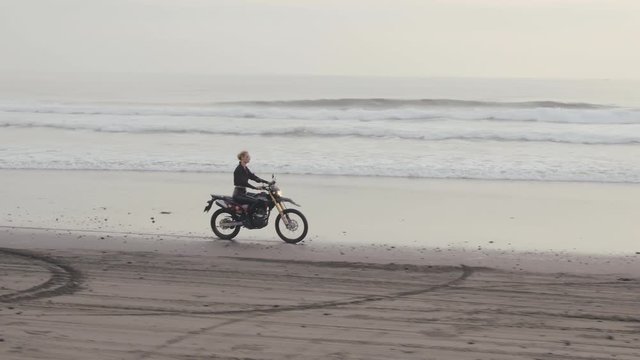 Aerial view of woman riding motorcycle on beach.