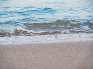 Water waves of Red Sea running on brown sand, close up view. Abstract nature background. Egyptian beach in february. Selective soft focus. Blurred background