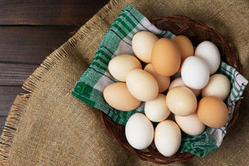 Top view of an eggs in a basket with a napkin on a wooden background.