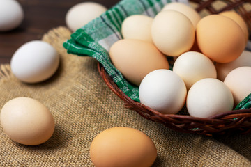 Eggs in a basket with a napkin on a wooden background.