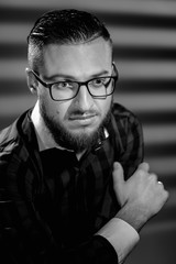 Obraz premium Portrait of young handsome smart man correcting glasses. image in black and white conversion
